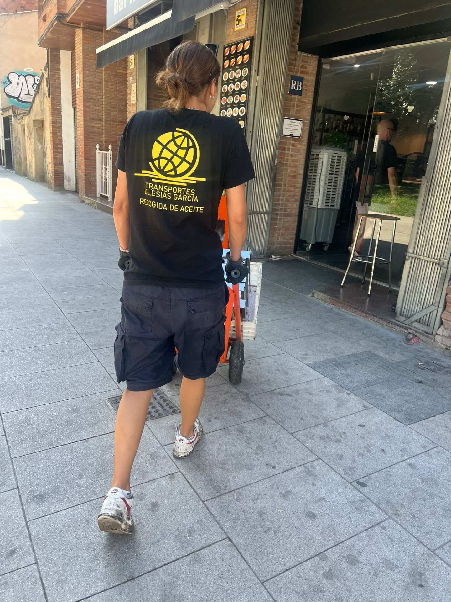 Operaria de Transportes Iglesias García realizando una recogida de aceite usado en la calle